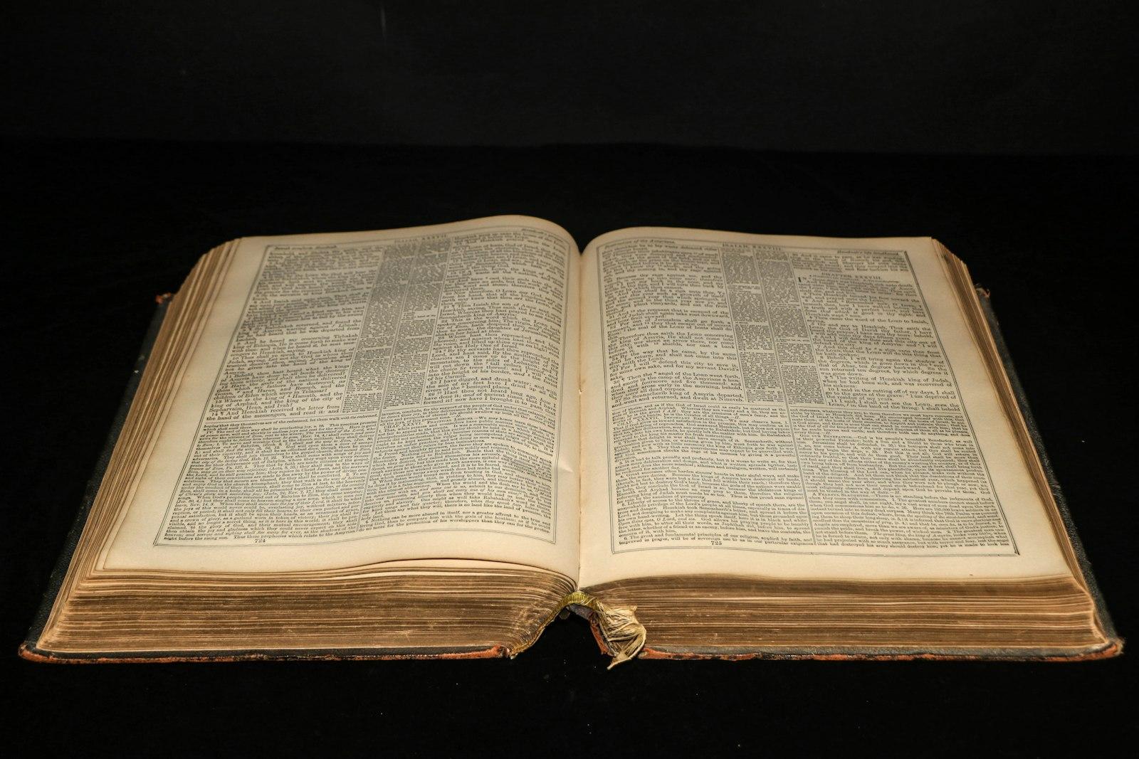 Un gros volume ancien relié, ouvert sur deux pages de texte en colonnes serrées